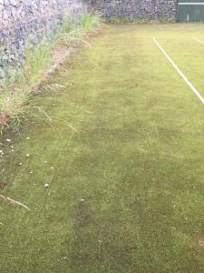 A worn synthetic tennis court before our professional maintenance services.